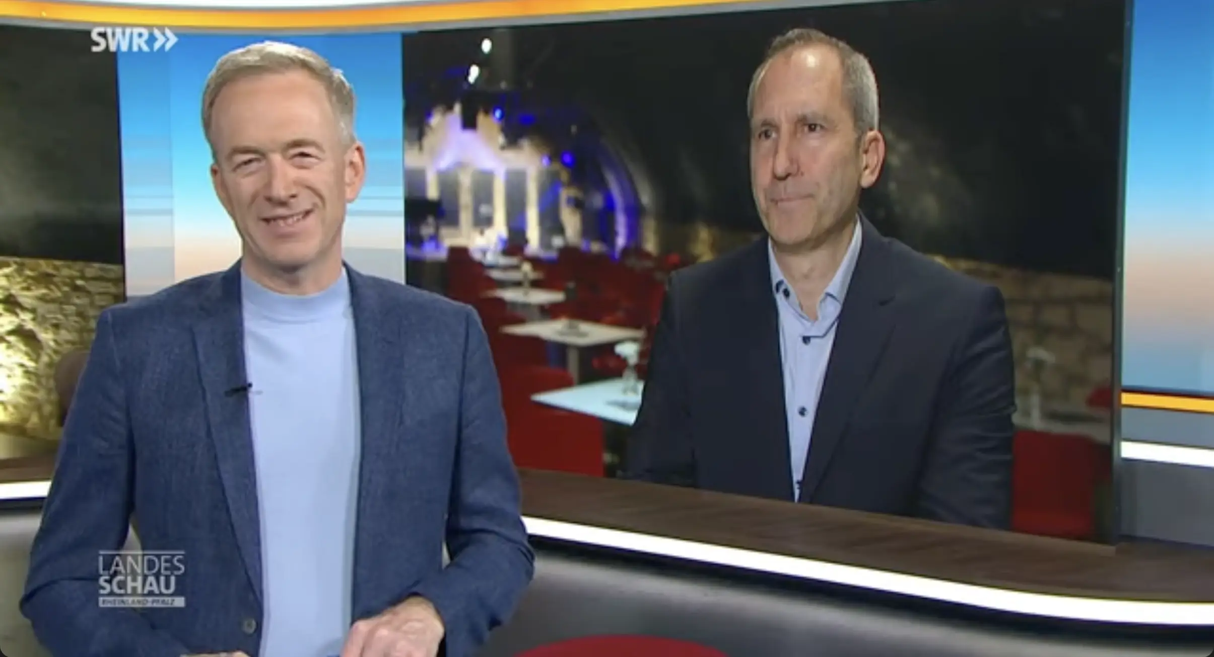 Zwei Männer im Fernsehstudio vor Bild des Gewölbekellers, Vorschaubild zum SWR-Landesschau-Beitrag
