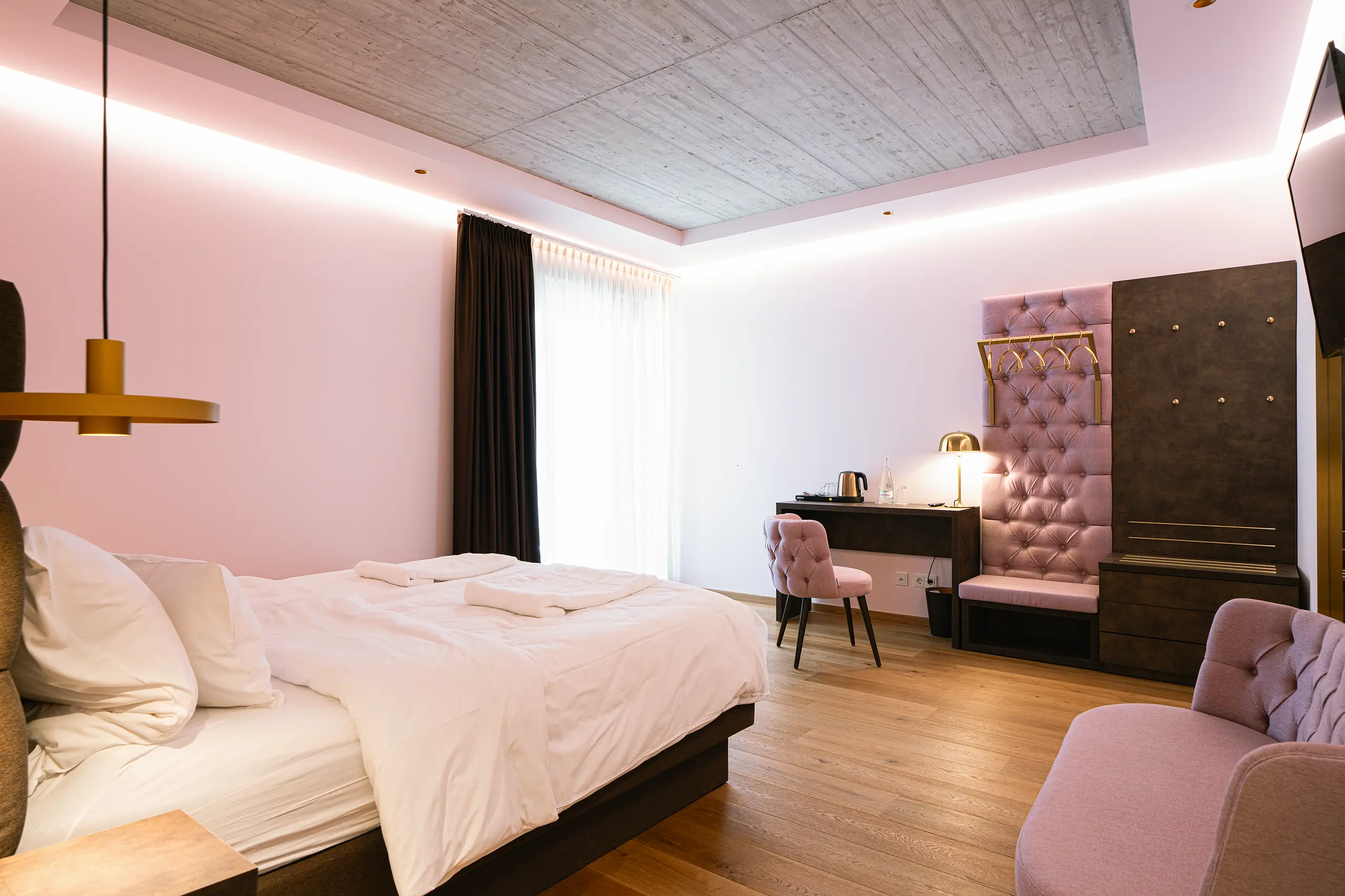 Superior-Zimmer im Neubau mit Doppelbett, Sitzecke und rosafarbener Beleuchtung
