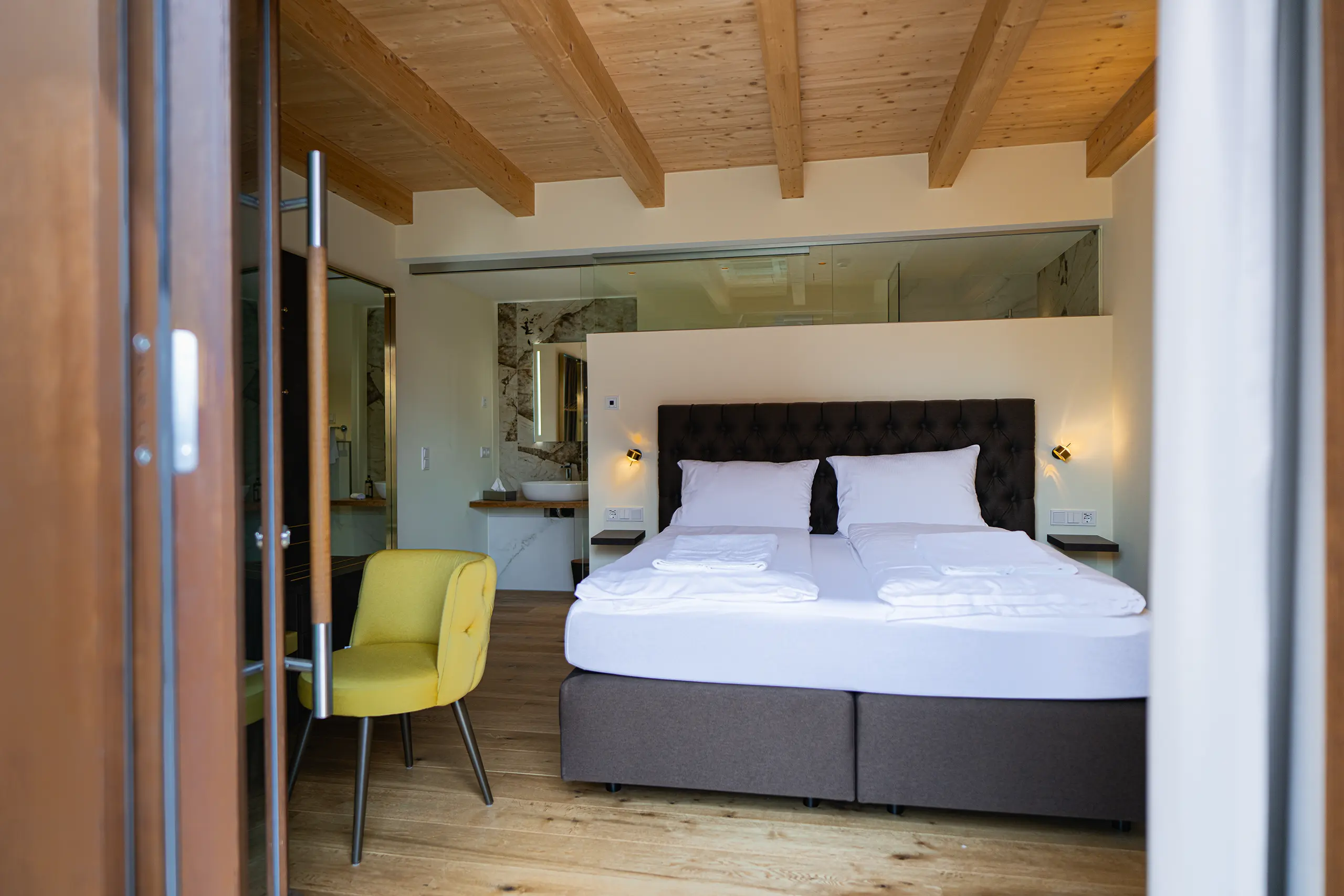 Superior-Zimmer 29 im Neubau mit Doppelbett, Holzdecke und gelbem Sessel