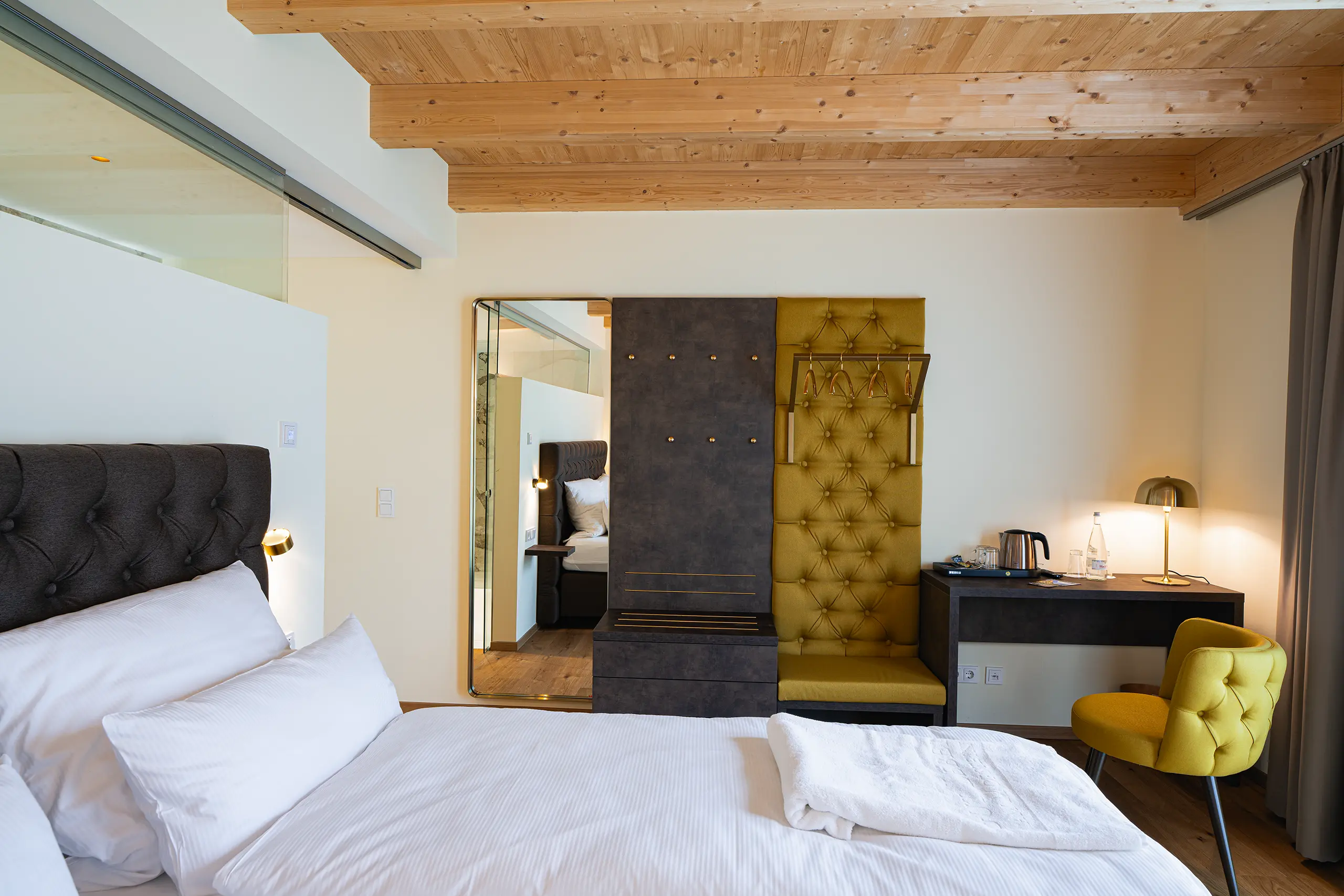 Superior-Zimmer 30 im Neubau mit Doppelbett, gepolsterter Wand und gelbem Sessel
