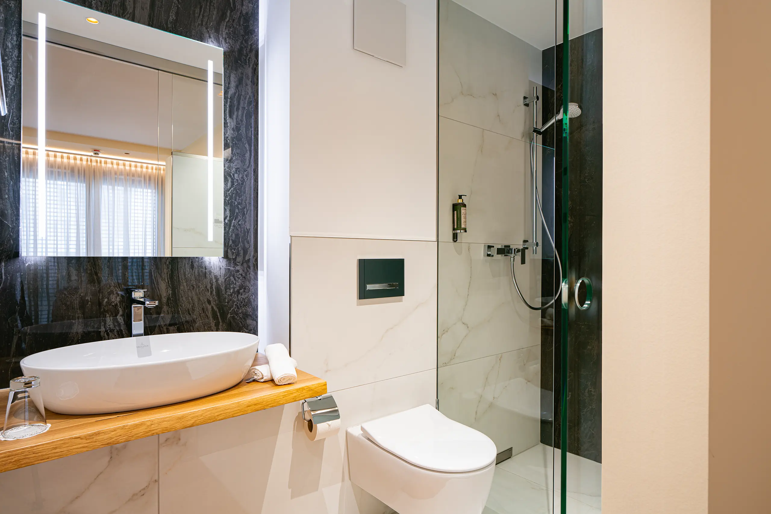 Badezimmer in Zimmer 31 im Neubau mit Waschbecken, WC und Glasdusche
