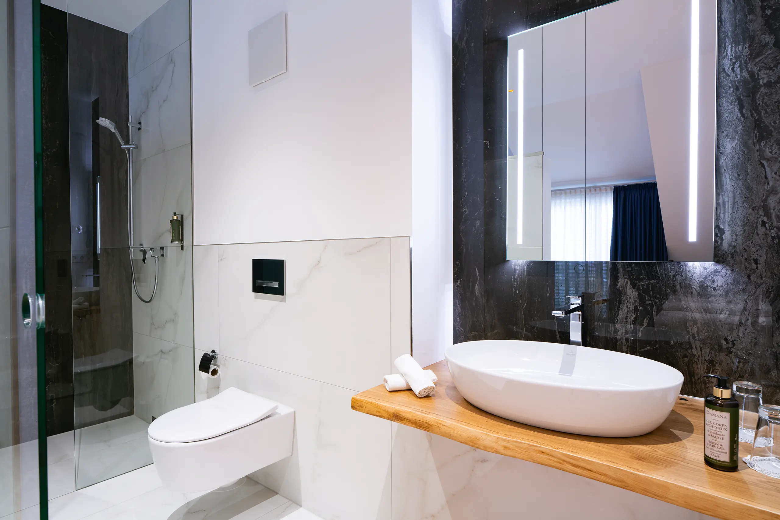 Badezimmer in Zimmer 40 im Neubau mit Waschbecken, Glasdusche und WC