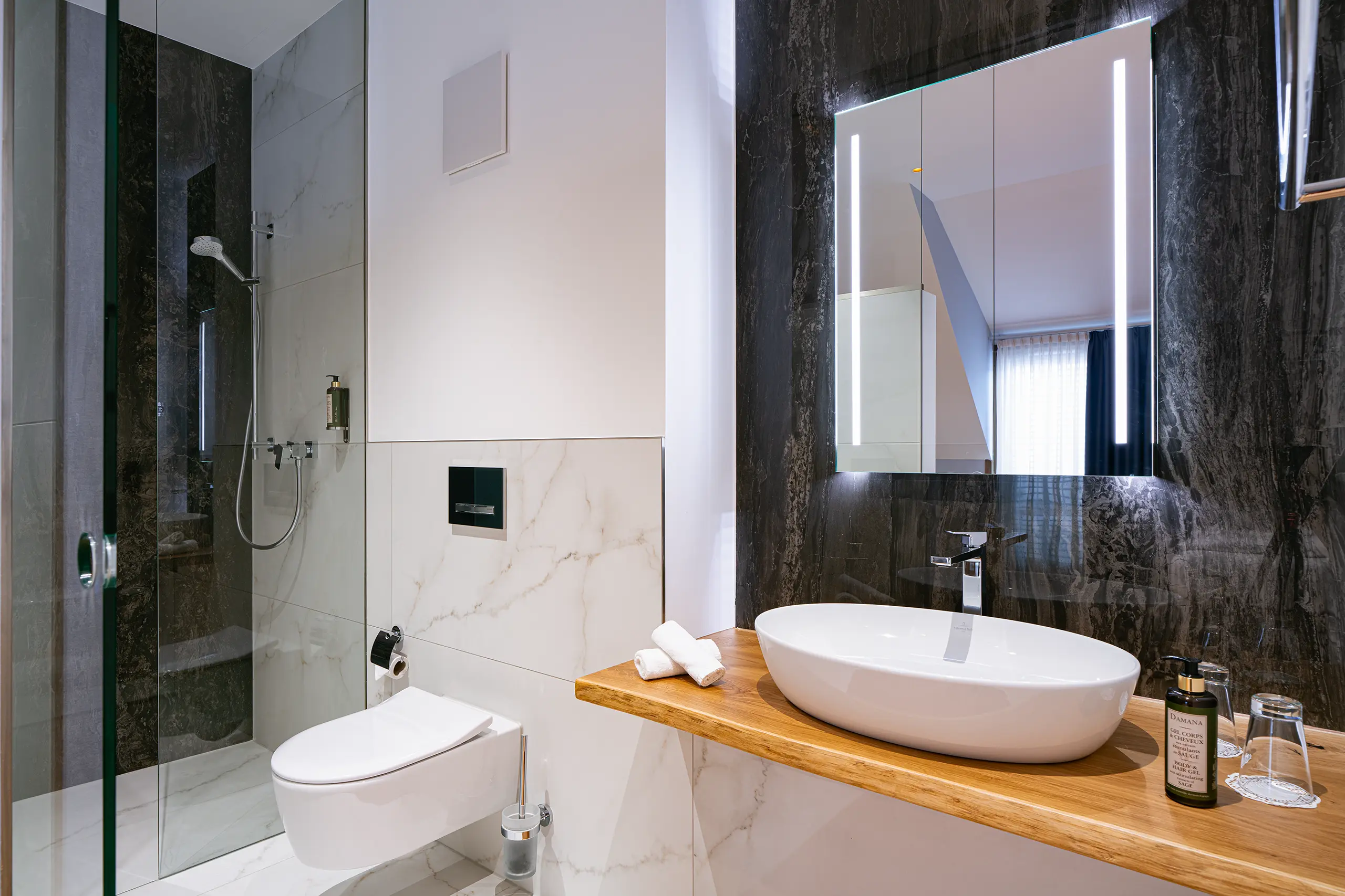 Badezimmer in Zimmer 41 im Neubau mit Waschbecken, Spiegel und Glasdusche