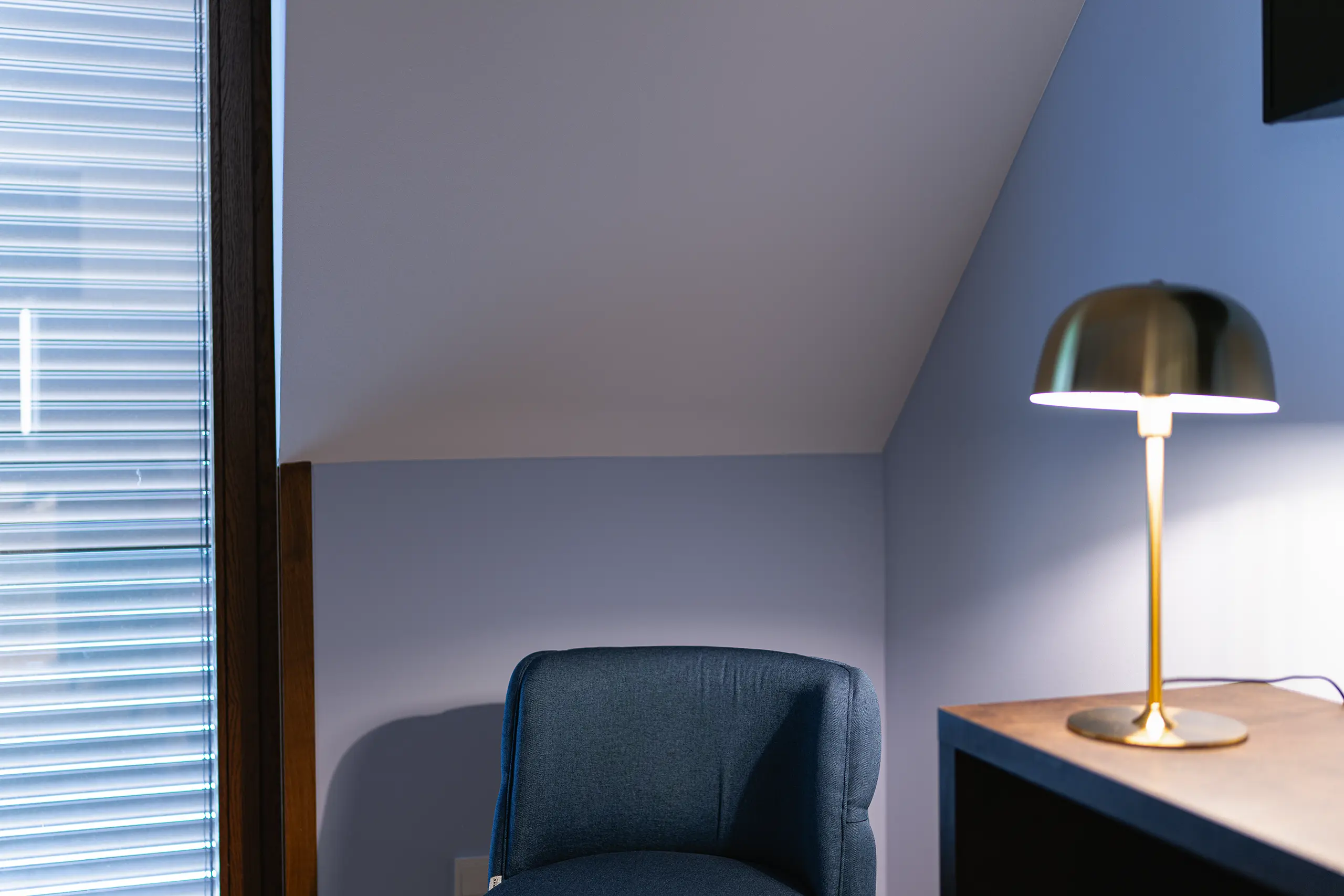 Blauer Sessel mit goldener Stehleuchte am Fenster in Zimmer 41 im Neubau