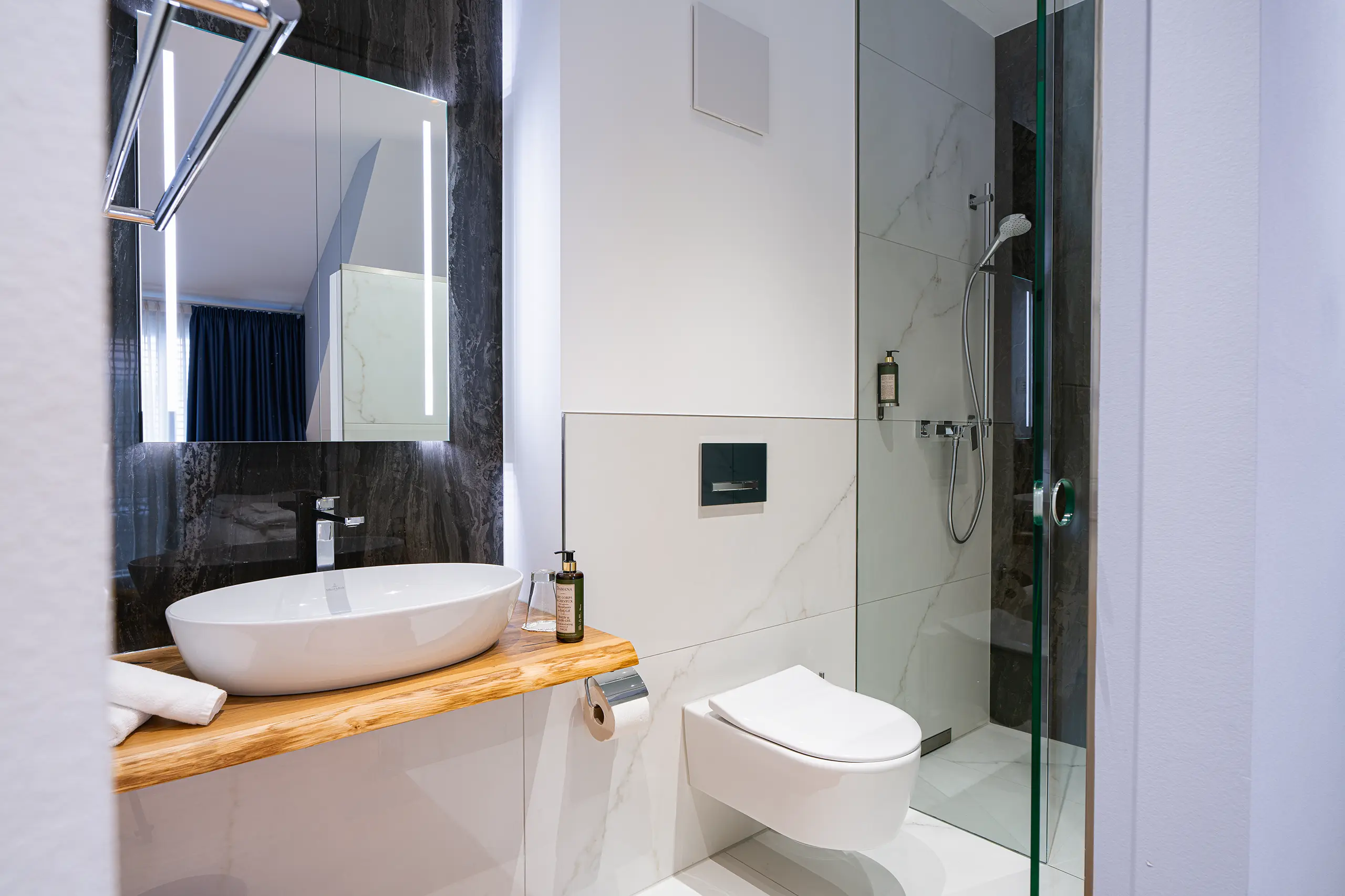 Badezimmer in Zimmer 42 im Neubau mit Waschbecken auf Holzplatte und Glasdusche