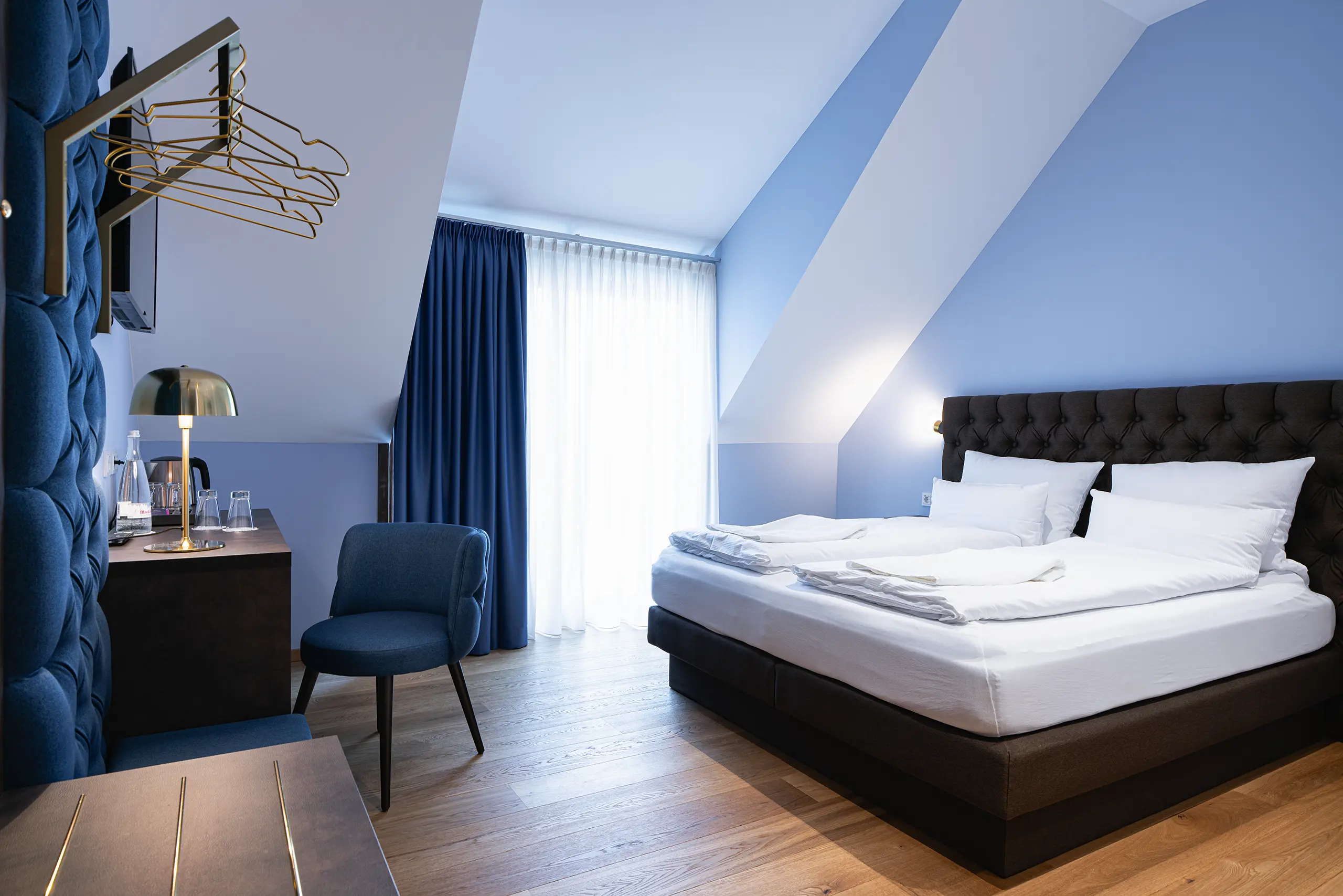 Superior-Zimmer 43 im Neubau unter der Dachschräge mit Doppelbett und blauem Sessel