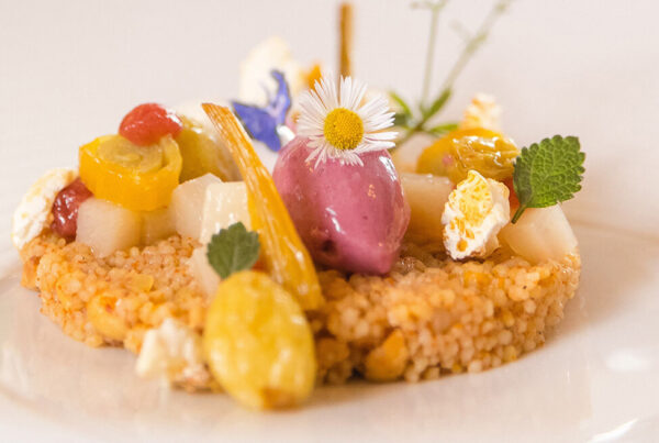 Kunstvoll angerichtetes Dessert mit Blüten und Sorbet auf weißem Teller