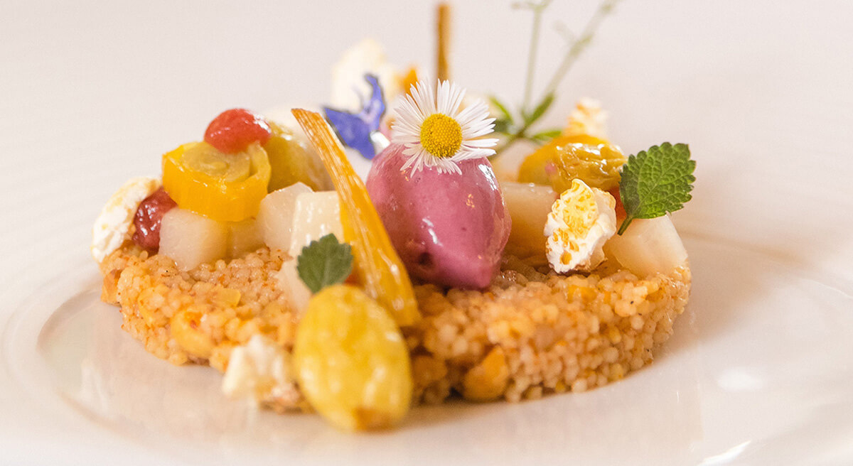 Kunstvoll angerichtetes Dessert mit Blüten und Sorbet auf weißem Teller