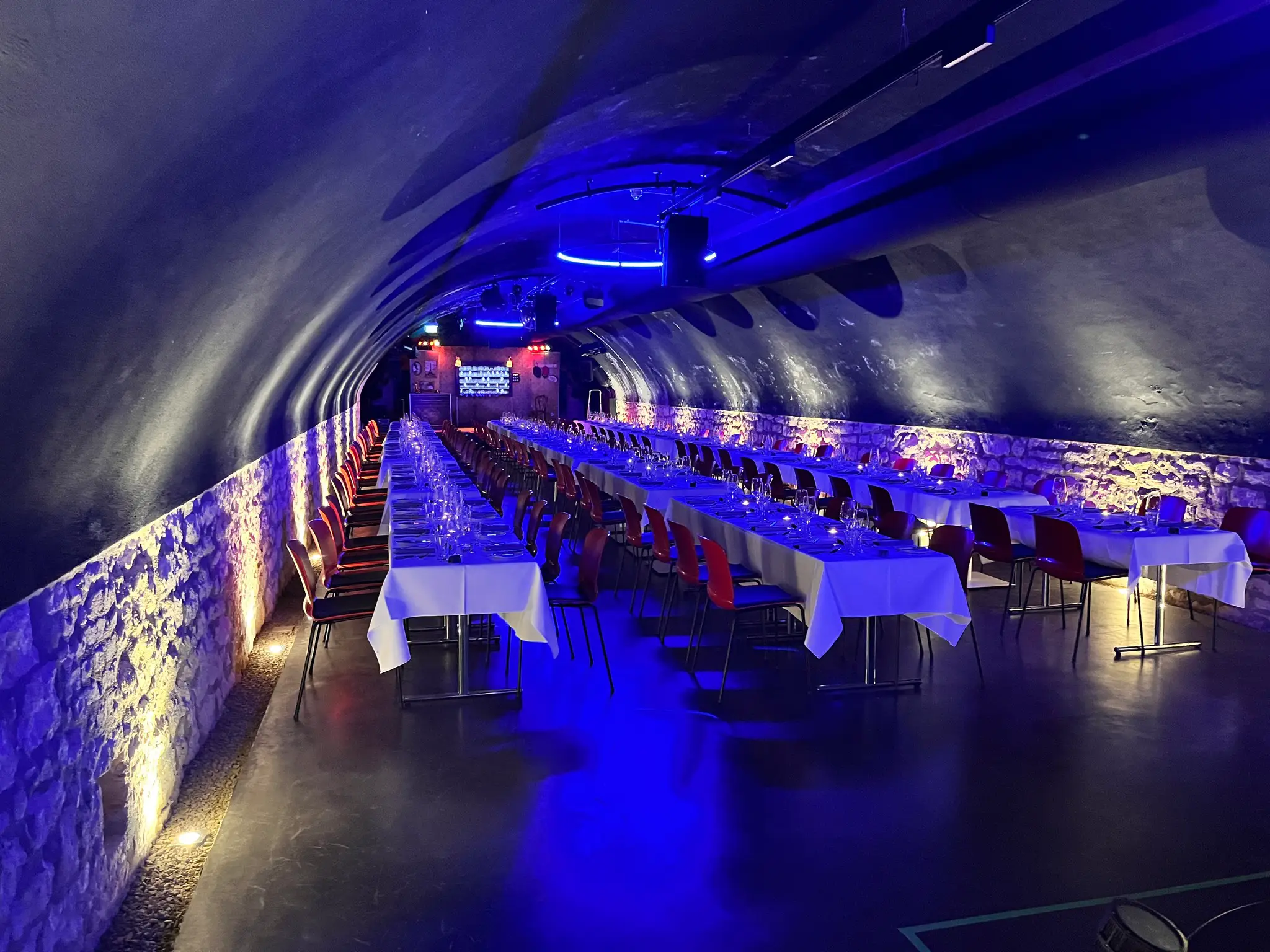 Gedeckte Tische im blau beleuchteten Gewölbekeller für ein Event-Dinner