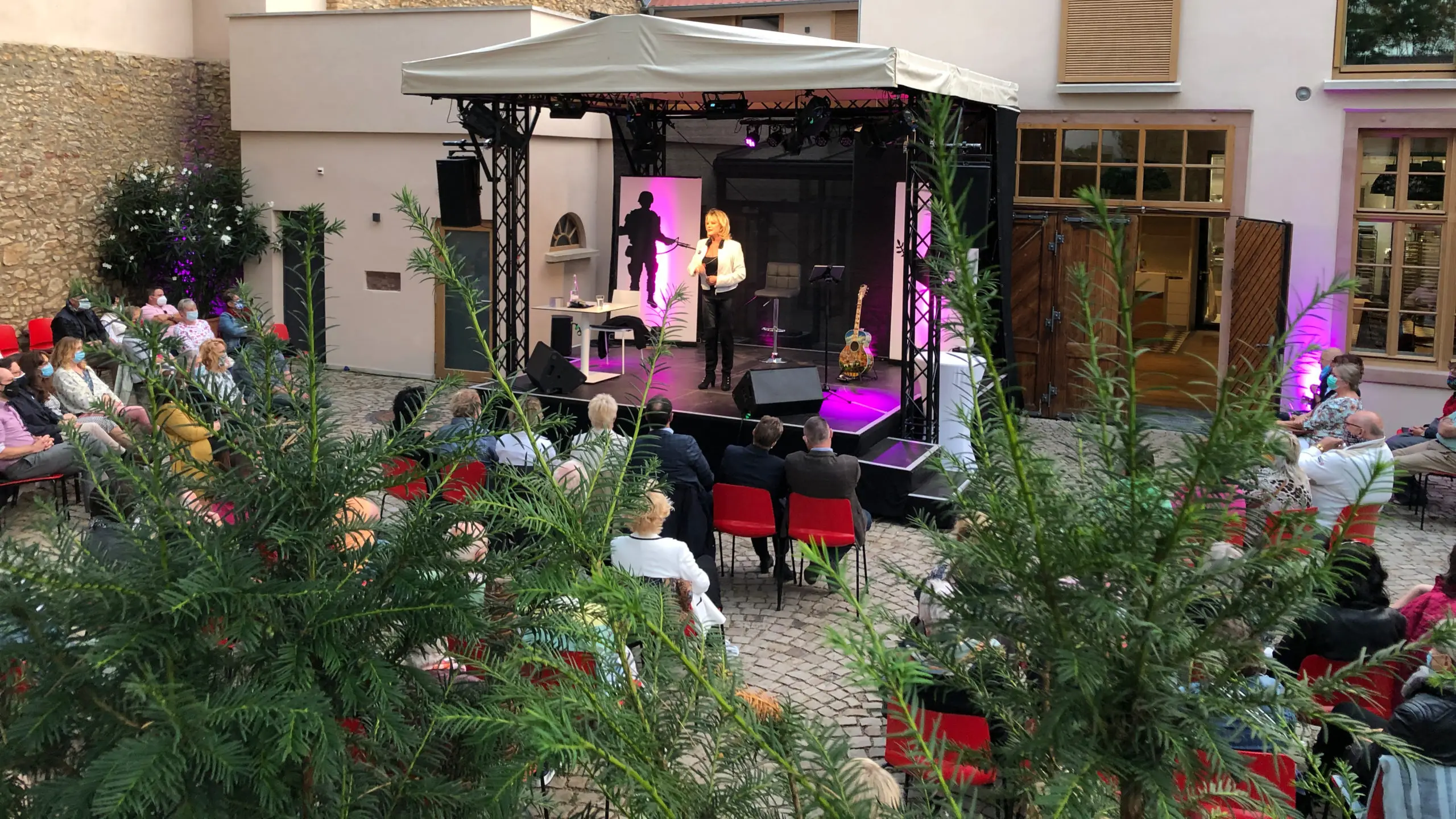 Konzert im Innenhof mit Sängerin auf der Bühne und Publikum an Tischen