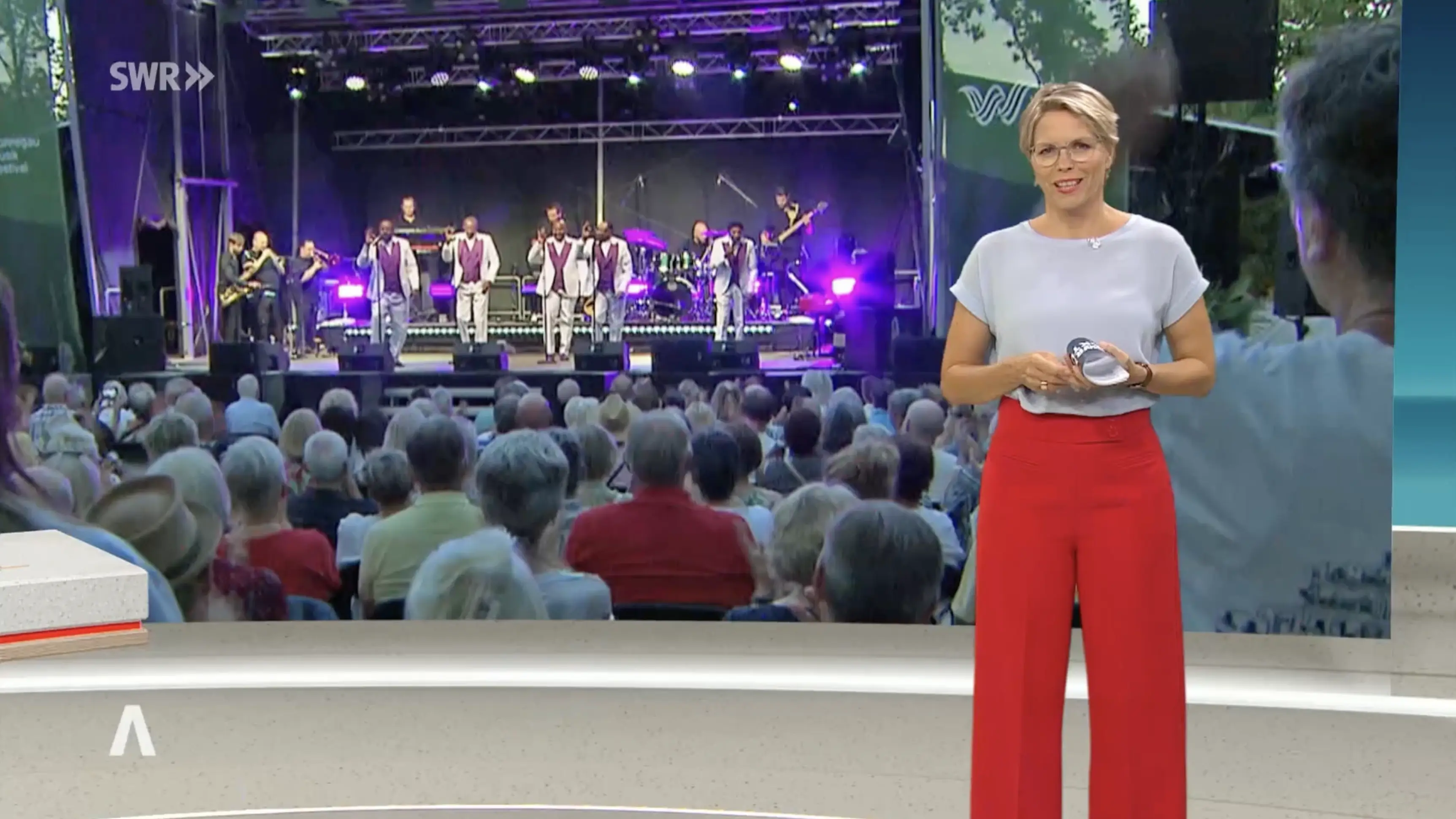 SWR-Moderatorin vor Konzertbühne mit Publikum, Vorschaubild zum Fernsehbeitrag